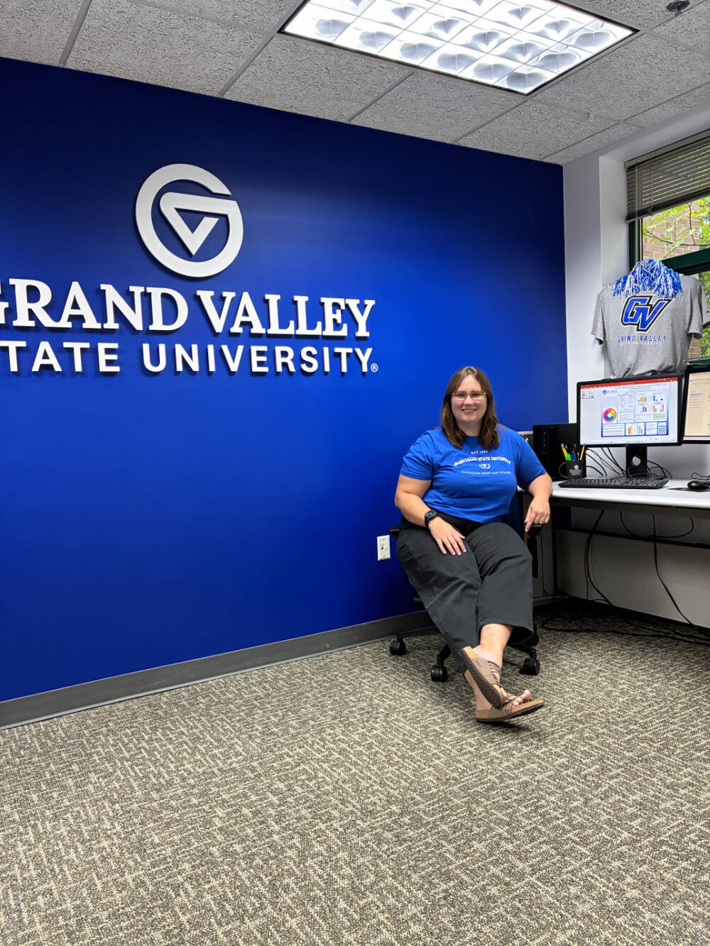 Sam Purifoy sitting at a desk with a blue wall behind her